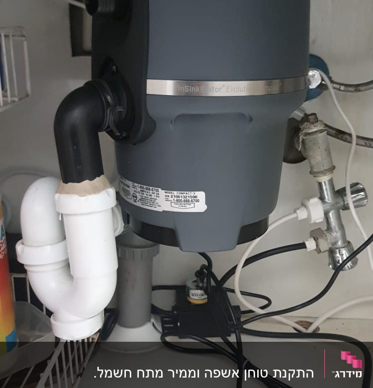 מכשיר טוחן אשפה מתחת לכיור עם צינורות חיבור